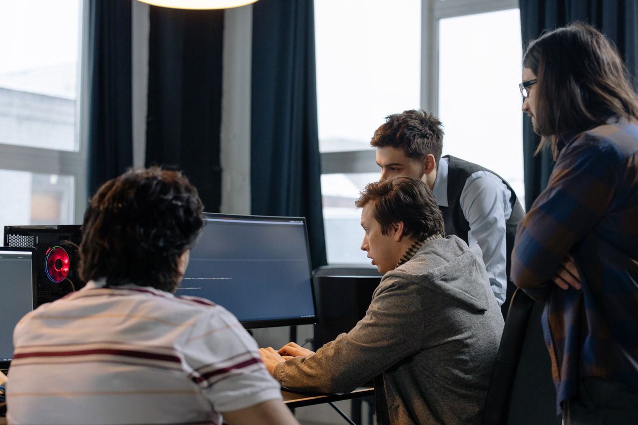 Services Group of developers working together on a computer programming project indoors.