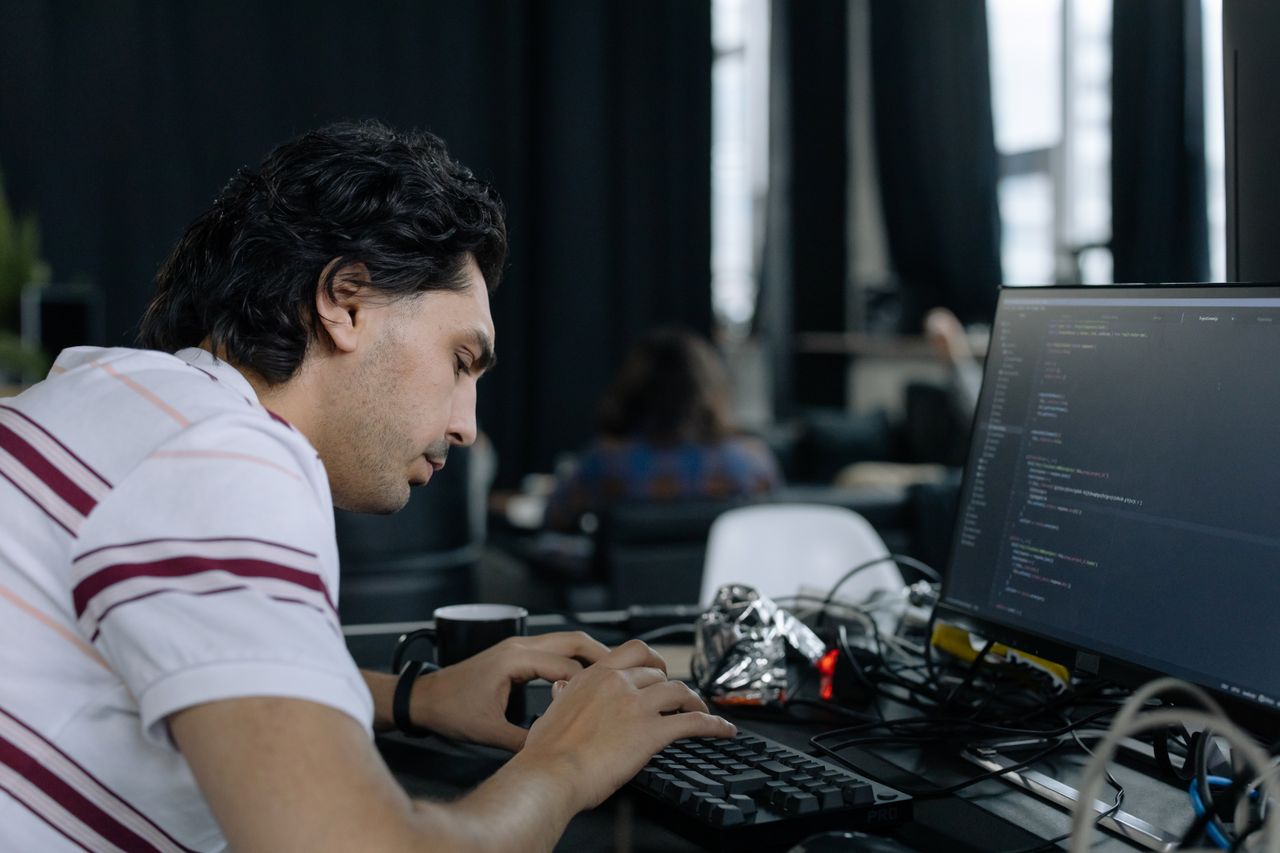 The Art of Drawing Readers In: Your attractive post title goes here A coder intensely typing at a workstation in a contemporary office setup.